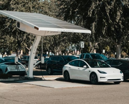 Electric car parked at a solar charging station outdoors, highlighting renewable energy and innovation.