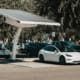Electric car parked at a solar charging station outdoors, highlighting renewable energy and innovation.