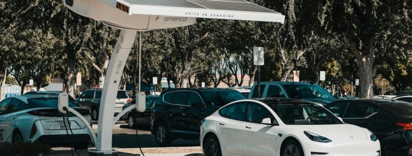 Electric car parked at a solar charging station outdoors, highlighting renewable energy and innovation.
