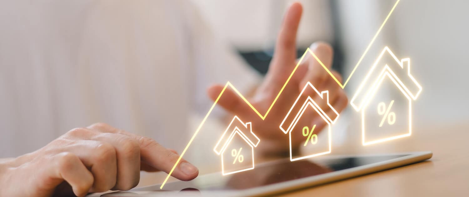 Property Valuations Toowoomba Property Valuations Toowoomba, A person uses a tablet with a glowing graph overlay showing rising house icons and percentage signs, symbolizing increasing real estate or mortgage rates in the Property Valuations Toowoomba market.
